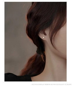 Gros plan d'une boucle d'oreille minimaliste ronde en argent plaqué or sur l'oreille