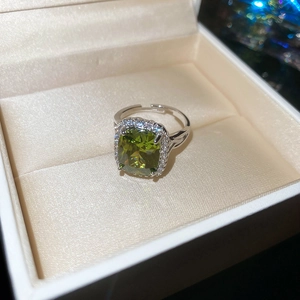 Macro shot of silver ring with olive green oval gemstone and micro-pave halo detail