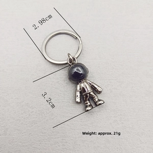 Close-up of astronaut keychain showing 3.2cm pendant size and 21g weight detail
