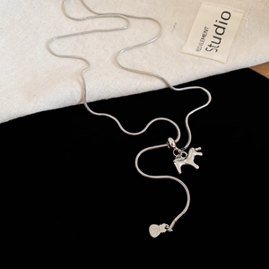 Detail of silver snake chain with minimalist pony pendant and fortune bag charm