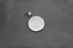 Close-up of minimalist round silver star pendant on a textured grey fabric background