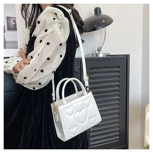 Vue détaillée du sac blanc en cuir PU avec motif de cœurs gaufrés et poignée supérieure