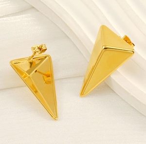 Macro view of 18K gold plated stainless steel triangle stud earrings on silk background