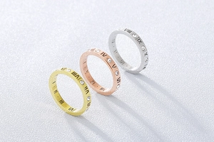 Détail de bagues en or rose 18k brossé avec chiffres romains et pierres en cristal