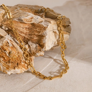 Minimalist gold paperclip chain necklace in stainless steel displayed on a natural rock