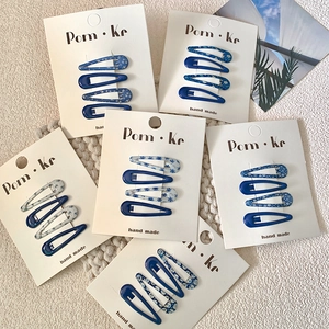 Floral and solid blue teardrop hair clips set on cards with a woven background