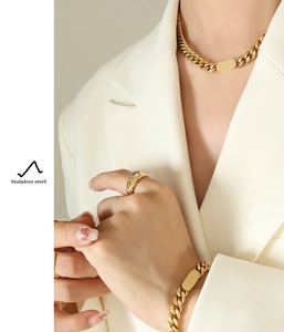 Détail d'un ensemble de bijoux gourmette dorés avec collier et bracelet portés par un mannequin