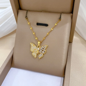 Élégant collier papillon doré avec micro-pavage de zircons dans un écrin à bijoux beige
