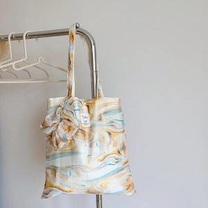 Detail of fabric tote bag with marble ink print and matching large scrunchie accessory