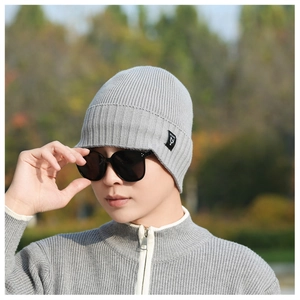 Close-up of light gray ribbed knit beanie with side black woven label for winter warmth