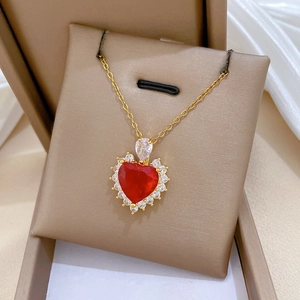 Macro shot of gold heart necklace with red zircon pendant and white crystal border