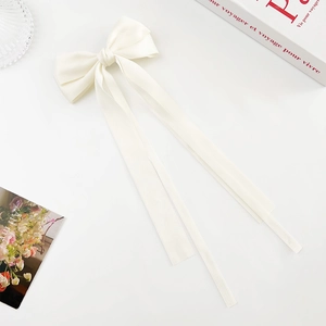Macro shot of cream white ribbon bow hair clip with elegant long satin streamers