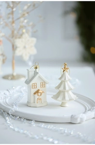 Detail of white ceramic Christmas tree and house figurines with gold accents on a tray