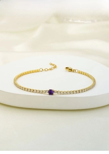 Detail of a gold titanium steel tennis bracelet with purple center stone and zircon inlay