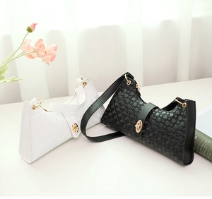 Detail of embossed geometric patterns on black and white underarm bags with gold hardware