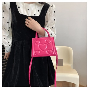 Gros plan du sac bandoulière rose avec motifs de cœurs en relief et similicuir lisse