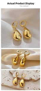 Macro detail of irregular gold teardrop earrings with crystals on textured travertine