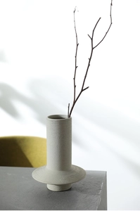 Detail of light gray ceramic vase with hand-carved spiral texture and wide ring base