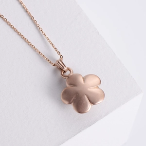 Rose gold 3D flower pendant necklace made of stainless steel on white pedestal
