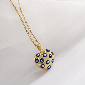 Detailed view of heart-shaped gold necklace with blue evil eye enamel patterns