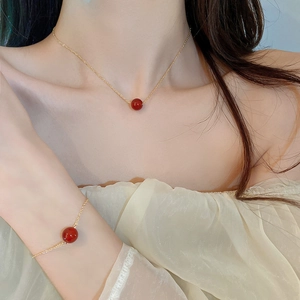 Detail von vergoldetem Halsketten- und Armband-Set mit roten Perlen am Model getragen