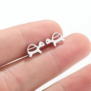 Minimalist stainless steel mini turtle stud earrings shown on finger for scale