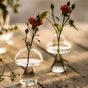 Nordic transparent mushroom glass vase set with red roses on a rustic wooden table