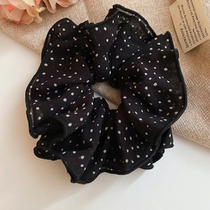 Detailed macro view of black chiffon hair scrunchie with white polka dot pattern design