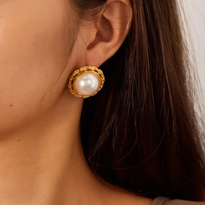 Vintage style gold plated pearl earrings with textured border on model's ear