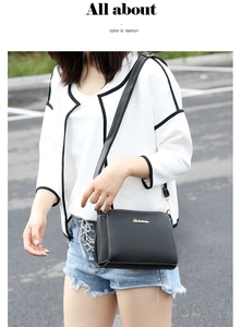 Detail of black PU leather shoulder bag with white stitching and gold hardware on model
