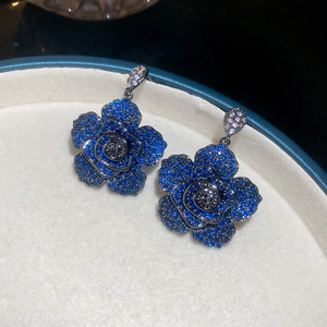 Macro detail of blue zircon flower earrings set in a soft velvet jewelry display box
