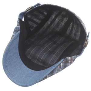 Detail of plaid beret hat with interior sweatband and vintage metal buckle on blue denim fabric