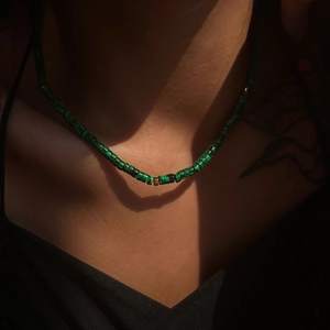 Green stone cylinder beaded necklace with gold metal spacers on model in dramatic lighting
