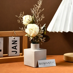 Modern square ceramic flower vase with white faux roses in a minimalist home decor setting