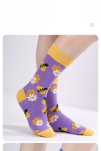 Detail of purple cotton crew socks featuring yellow bees, white daisies and honeycomb patterns