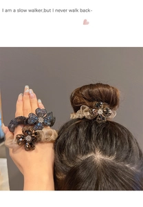 Macro detail of sparkly rhinestone clover scrunchie hair tie on model's hand and hair
