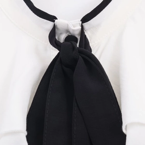Detail of white shirt collar with black contrast trim and silk-like bow tie design