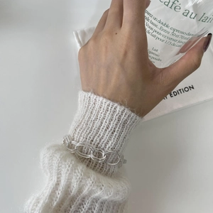 Polished silver double oval link chain bracelet styled on a white knitted sweater sleeve