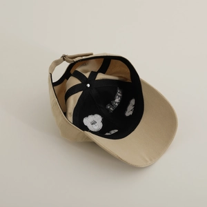 Detailed interior of a beige kids baseball cap with bear print and adjustable metal buckle