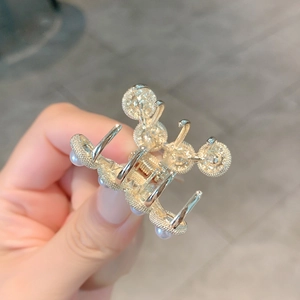 French palace style golden hair claw clip with pearls and rhinestones on a gray background