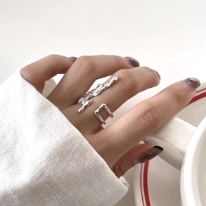 Detail of irregular textured silver ring with lava design worn on finger