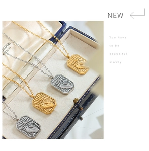Detailed view of square relief pendants in gold and silver within a blue vintage jewelry box