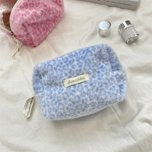 Detail of plush leopard print makeup bags in light blue and pink with a soft texture