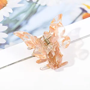 Detail of butterfly hair claw with orange marble acetate texture and gold spring