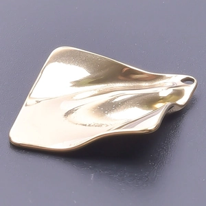 Macro view of a gold wavy geometric pendant with a high-polished metallic finish