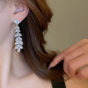 Close-up of silver leaf tassel earrings with clear zircon stones on a female model