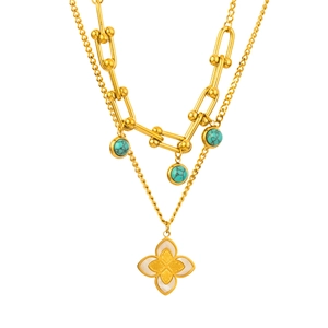 Dettaglio collana dorata a strati con maglie a U, perle turchesi e pendente a fiore