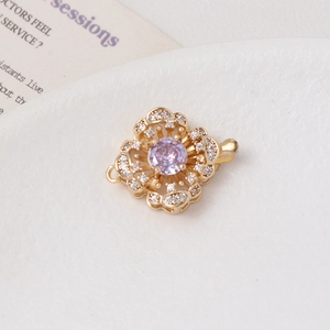 Detailed view of flower-shaped gold clasp with purple gemstone and white zircon stones