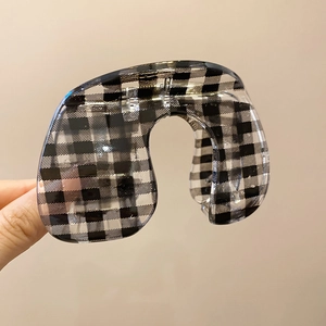 Detail of checkered acrylic hair claw clip with glossy finish held by hand