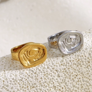 Detail of 18K gold and silver rings with irregular texture on a white stone background